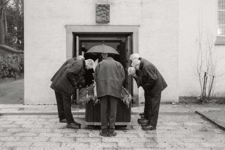 Sargträger verbeugen sich vor einem Sarg