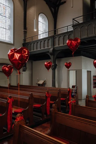 Mit Herzluftballons geschmückte Kirchbänke